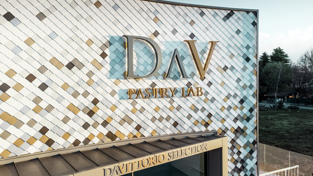 Bedriftsbygningen DAV Pastry Lab i Bergamo med spettet rombefasade i fargene P.10 brun, bronse, P.10 mørk grå, mayagull, naturblank, P.10 prefahvit og P.10 ren hvit. 