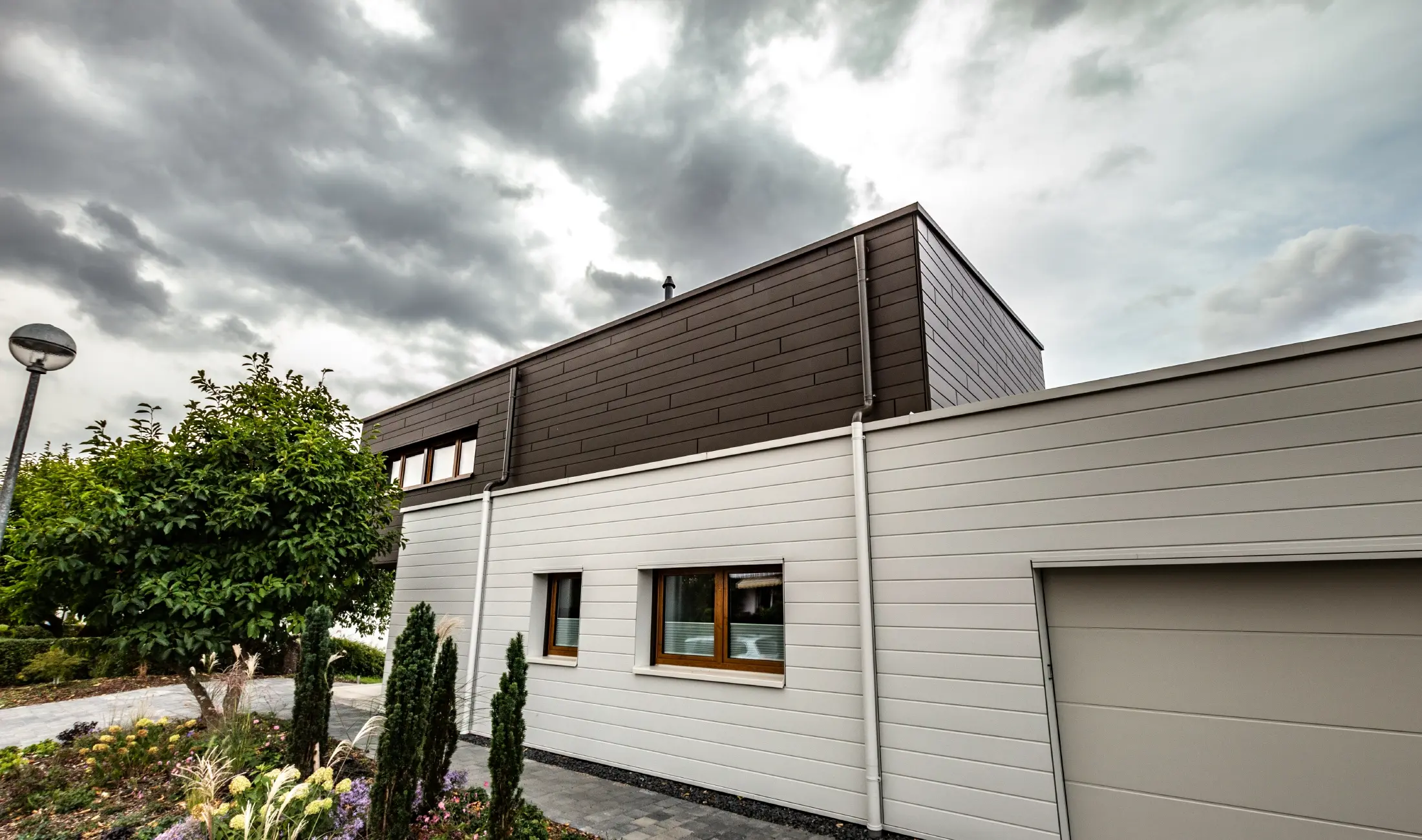 Fasadekledning på en garasje med PREFA Siding liggende i hvit, med regnmottaker.
