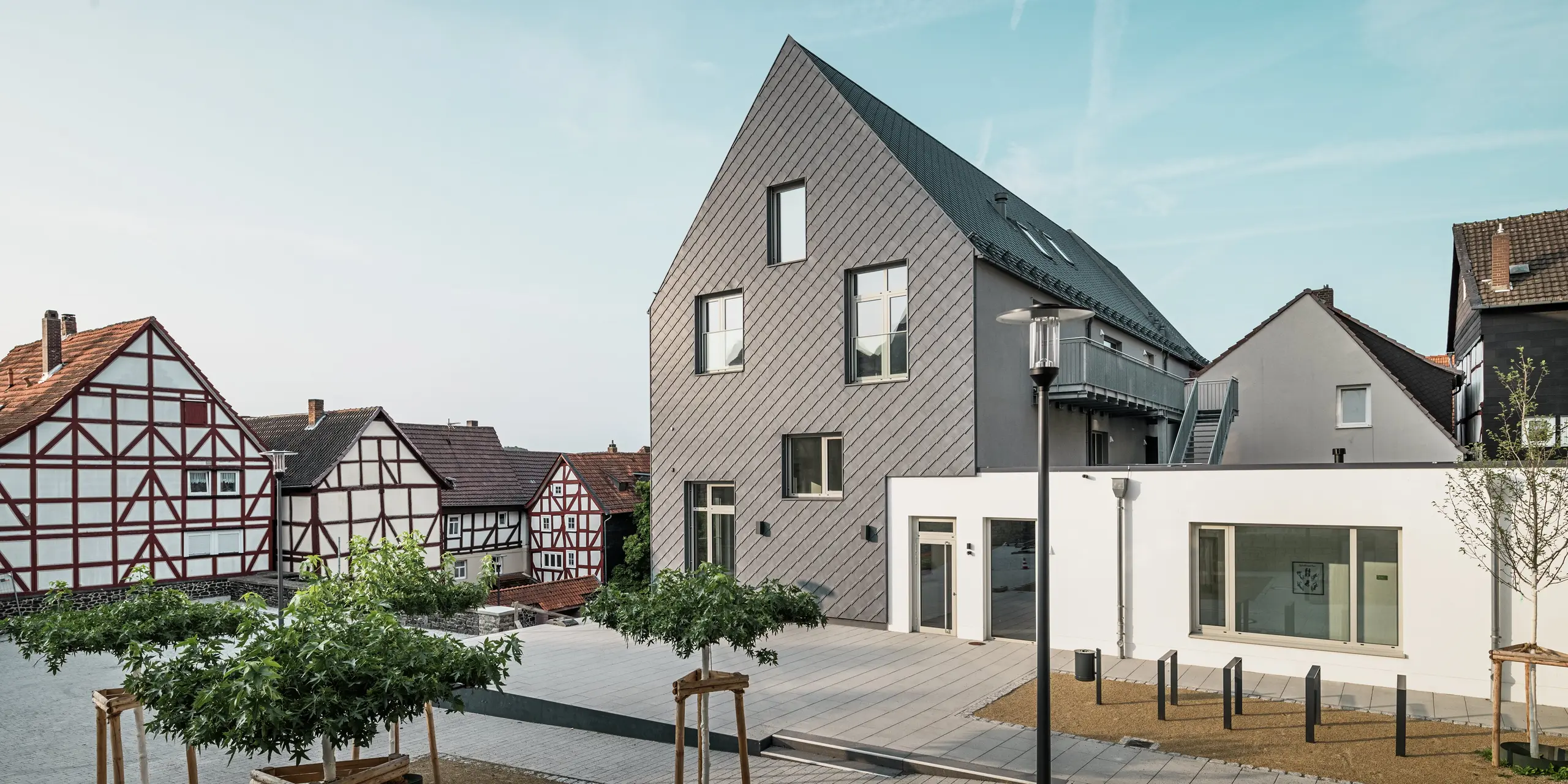 Rückansicht des modernisierten Volkshauses in Homberg, DE, mit PREFA Wandrauten 29 × 29 in P.10 Steingrau. Die elegante Fassade verbindet modernes Design mit den historischen Fachwerkhäusern der Umgebung und bietet Witterungsschutz, Langlebigkeit und zeitlose Ästhetik.