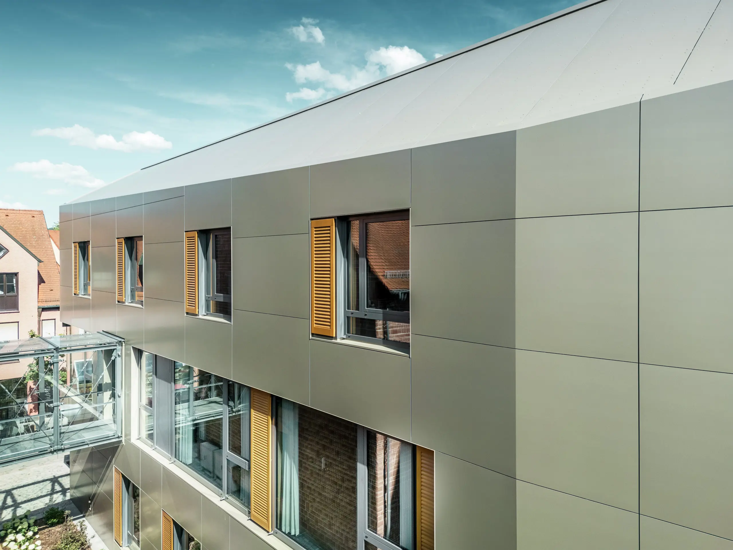 Das Bild zeigt einen Ausschnitt der Fassade des Rathauses in Alzenau, die mit PREFA-Aluminiumverbundplatten in Bronze verkleidet ist. Die Platten sind in einem modernen, rechteckigen Muster angeordnet.