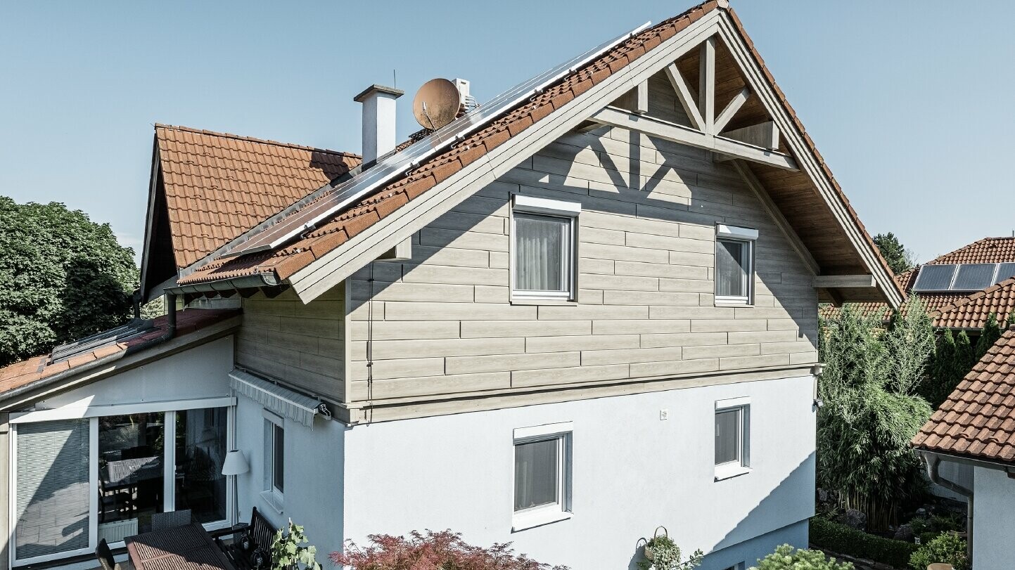 Nyrenovert fasade med luftet aluminiumsfasade i overetasjen; gavlen ble kledd med sidings i trefinish (beige-grå eik). 