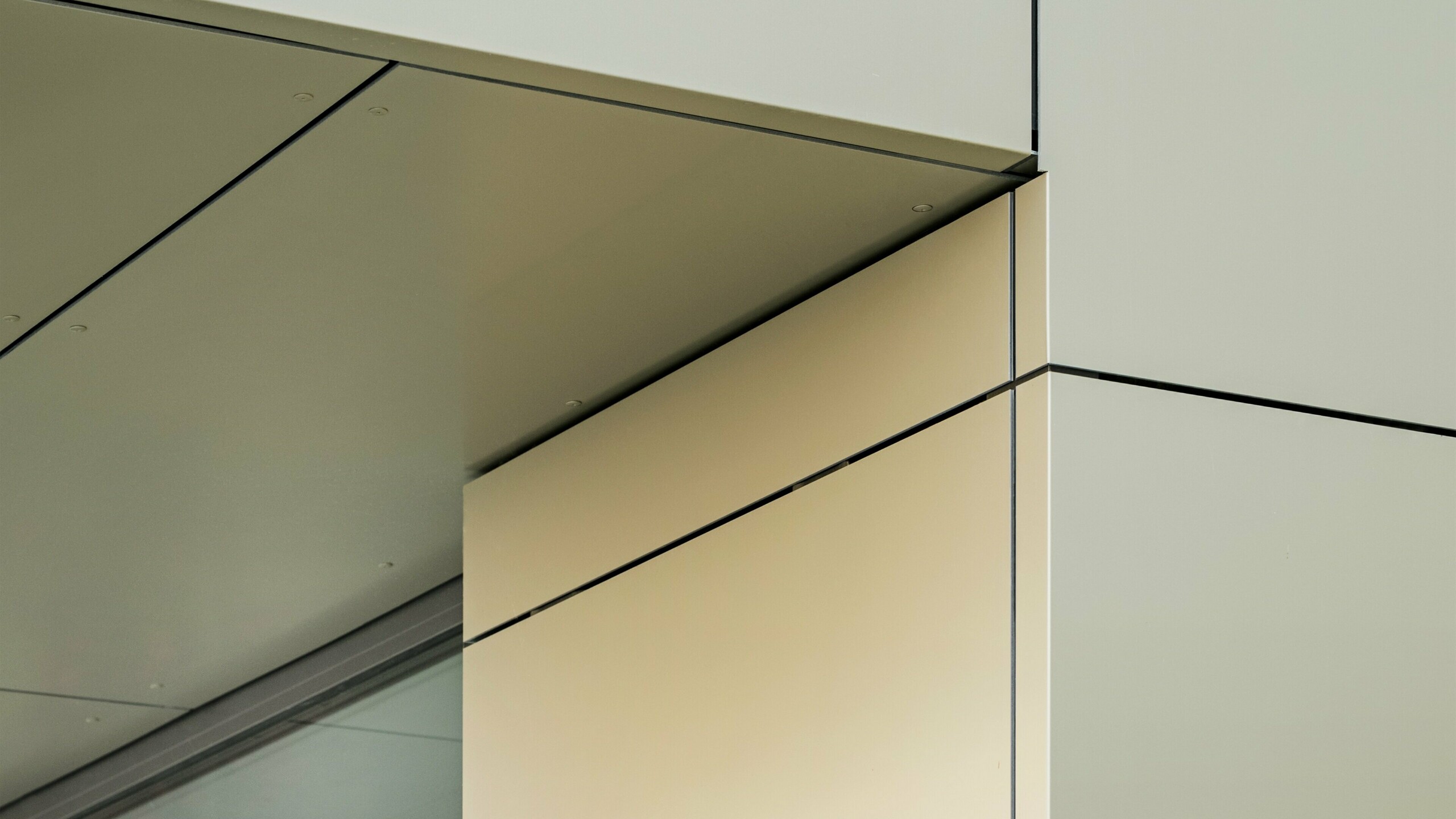 Detaljni prikaz fasade gradske vijećnice u Alzenauu, koji prikazuje precizne rubove i prijelaze PREFA aluminijskih kompozitnih ploča u brončanoj boji. Ploče su savršeno spojene, stvarajući jasne, moderne linije. Metalik sjaj ploča naglašavaju fini spojevi i minimalistički detalji arhitekture, što fasadi daje elegantan i suvremen izgled.