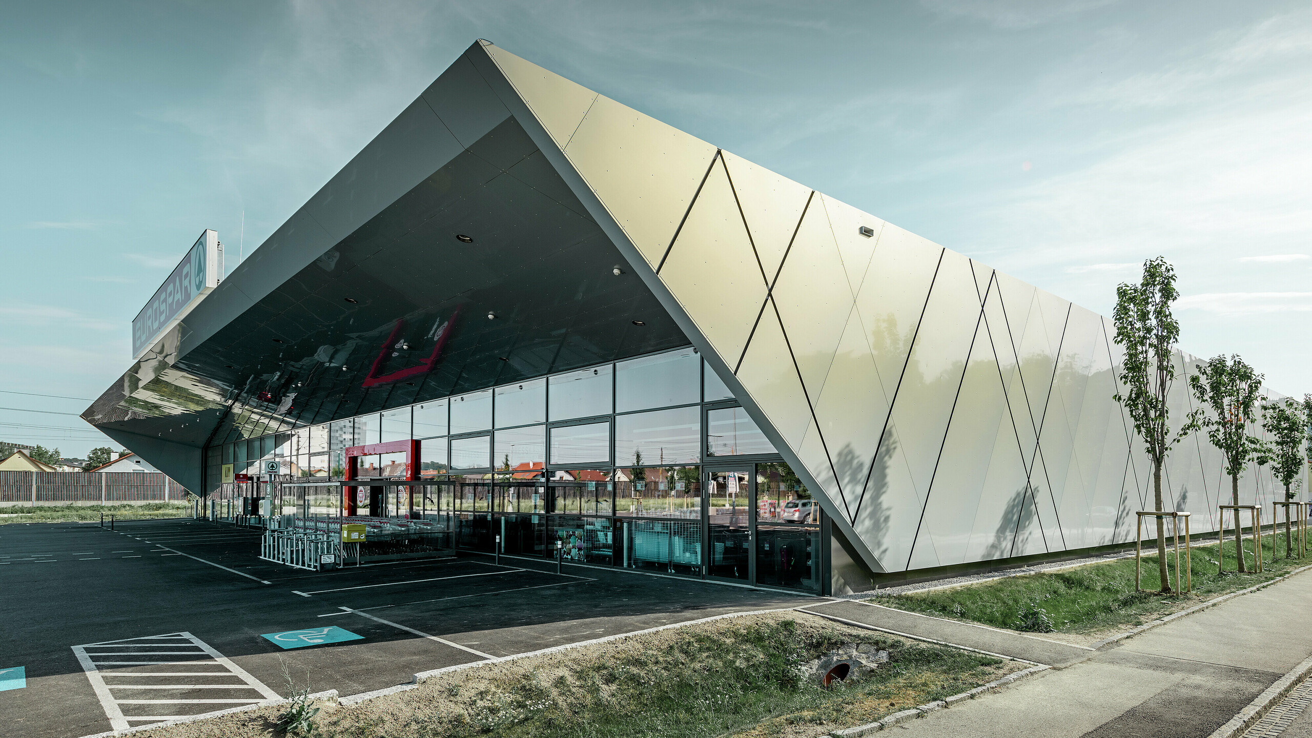 Inngangspartiet til den nye Eurospar filialen i Wels med den moderne fasadeplaten fra PREFA i sølv og gull. Aluminiumskomposittplatene funkler i solen i forskjellige farger alt etter fra hvilken vinkel man ser.