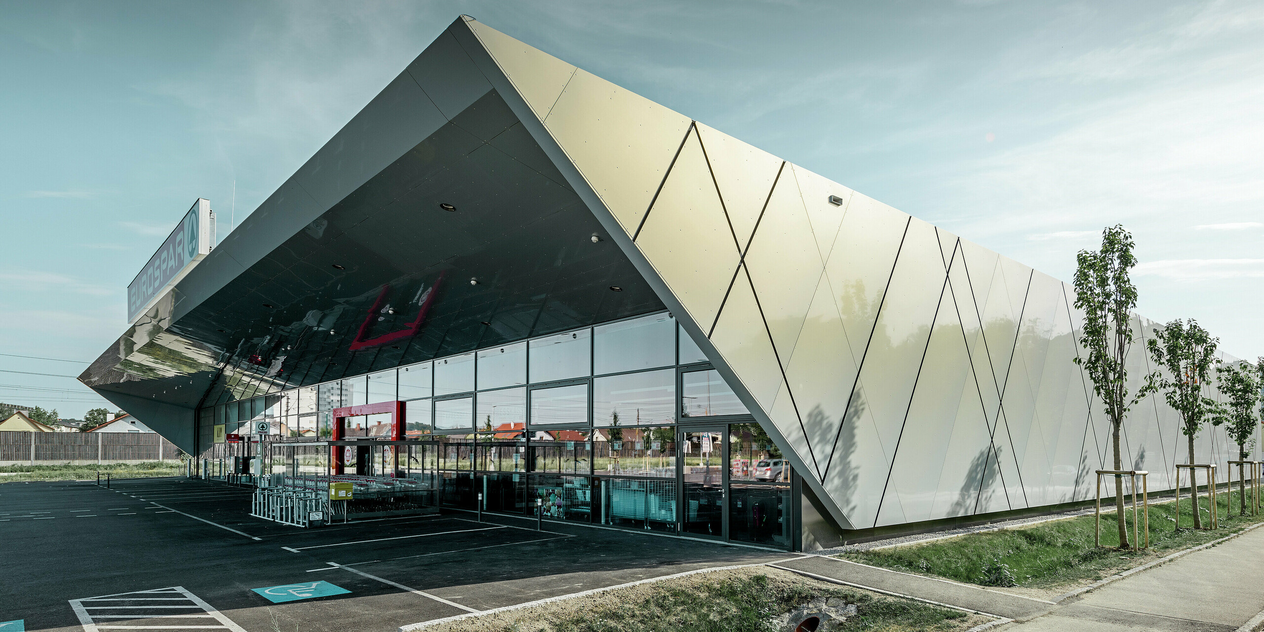 Inngangspartiet til den nye Eurospar filialen i Wels med den moderne fasadeplaten fra PREFA i sølv og gull. Aluminiumskomposittplatene funkler i solen i forskjellige farger alt etter fra hvilken vinkel man ser.