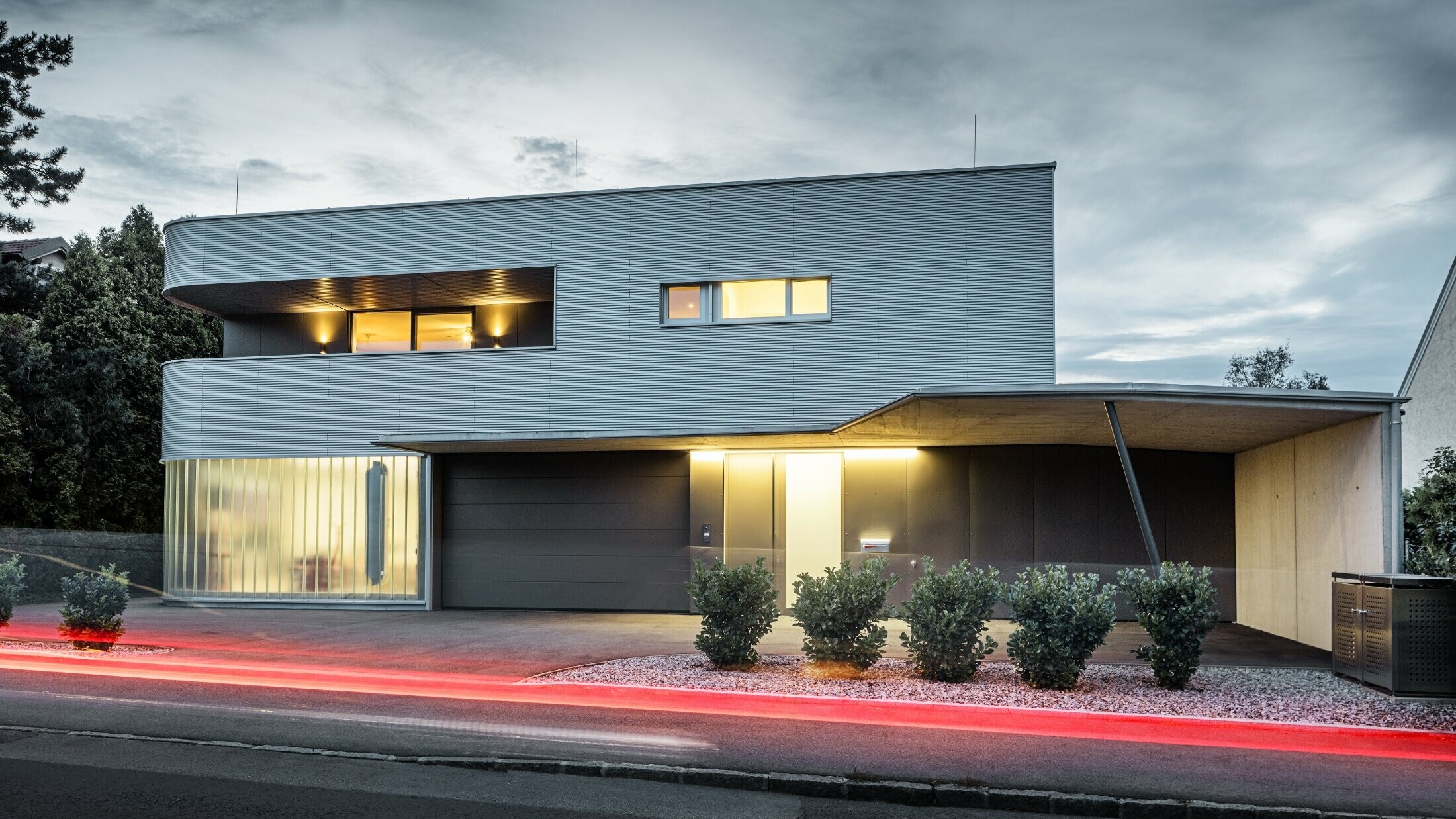 Moderne bolig med naturblank fasade i PREFA bølgeprofil med garasje fotografert i kveldslys