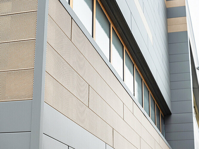 Fasadepanelene fra PREFA, Siding, fås nå også i perforert, altså hullet utførelse, her er sandbrune, perforerte elementer kombinert med grå paneler. 