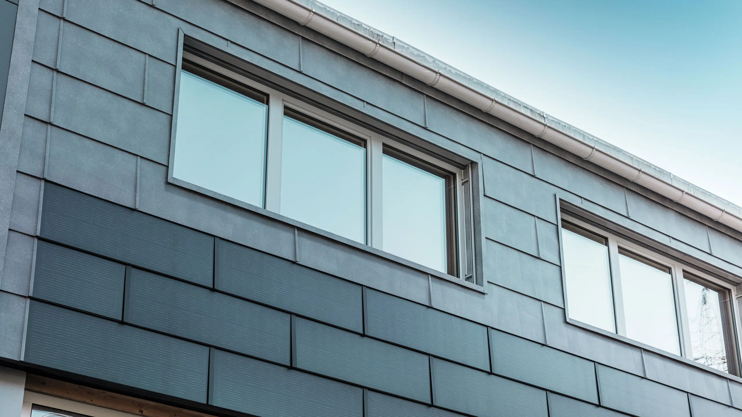 Fasadeflaten på firmaets bygning ble kledd med innovative solcelle takplate kombinert med fasadepanel FX.12 fra PREFA.