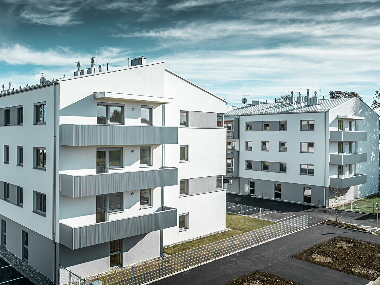 Moderne boligkompleks med hvit fasade og balkonger med PREFA sikksakkprofil i sølvmetallic