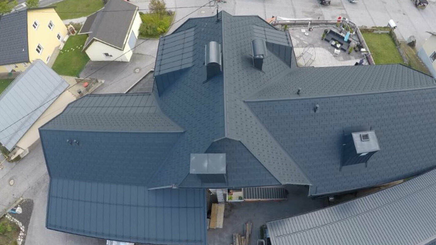 Renovering av en stor takflate med mange detaljer – søkk, kvister og skorstein. Taket er dekket med aluminiumstakplaten R.16 fra PREFA i antrasitt.