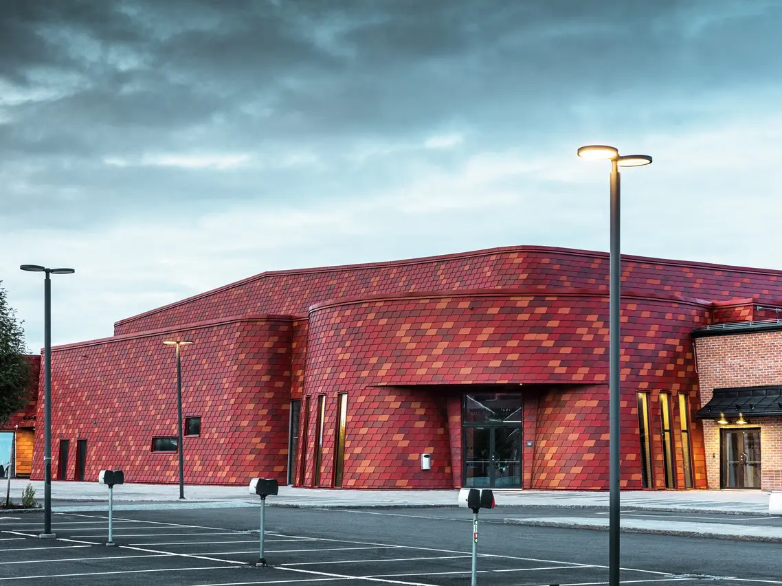 Aufnahme der Eis- und Eventhalle in Schweden. Für die Fassade wurde die PREFA Wandschindel in den Farben P.10 Oxydrot und zwei Sonderfarben Rotbraun und Braunrot verwendet.