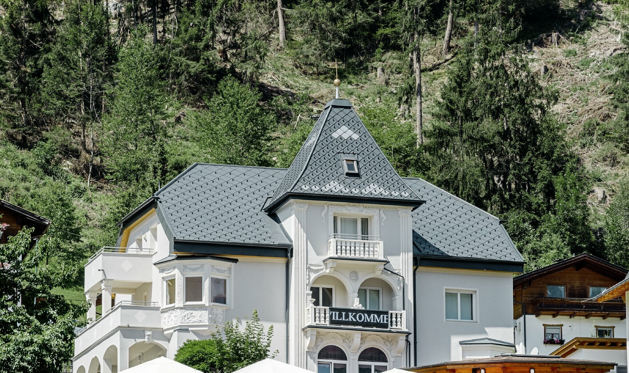 Felsenhaus mit Turm und einem Aluminiumdach in anthrazit mit einer Pizzeria im Erdgeschoss