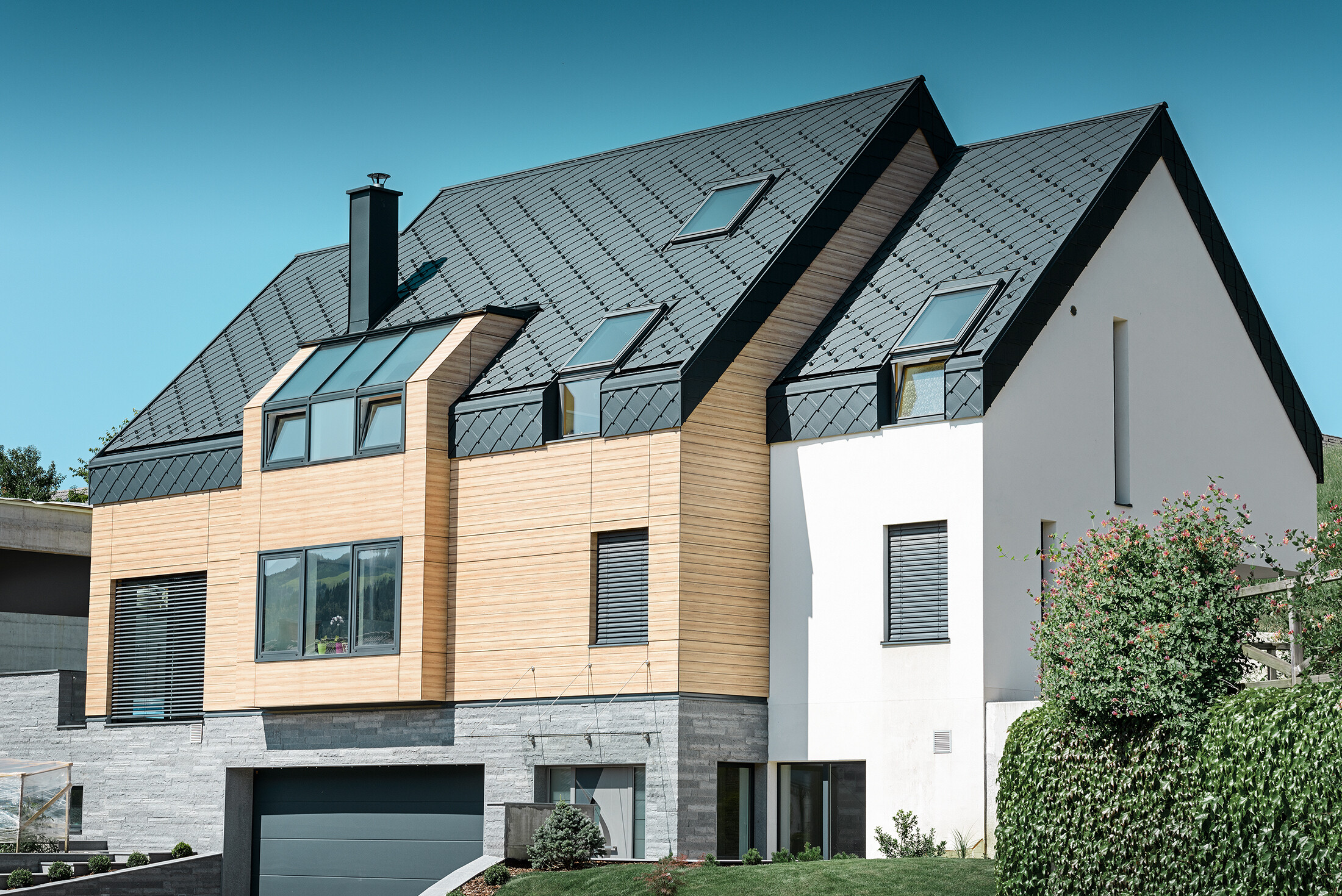 Moderne nybygg der takbekledningen også trekkes over fasadens øvre del. Aluminiums-takromben i antrasitt ble valgt til taktekkingen.