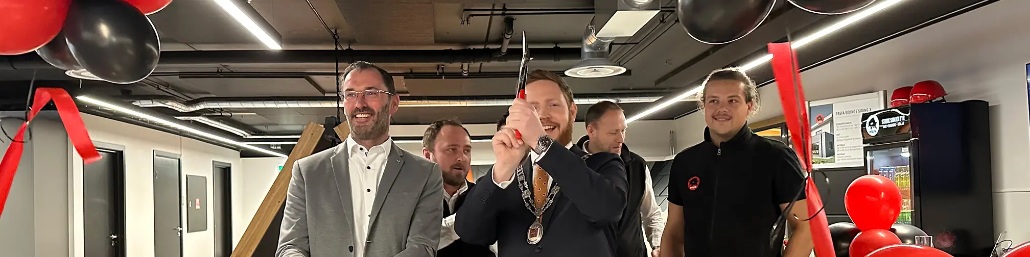Berthold Ruck, technischer Leiter von PREFA, und der Bürgermeister von Skien beim Durchschneiden des Bandes zur feierlichen Eröffnung der PREFA Academy in Skien. Im Hintergrund sind das PREFA Academy Team aus Norwegen und PREFA Mitarbeiter zu sehen.