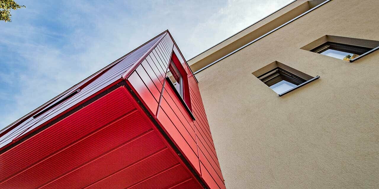 Karnapp med linjert PREFA Siding i rubinrød på en moderne enebolig i Wernigerode, her er undersiden fotografert på det utkragende tilbygget.