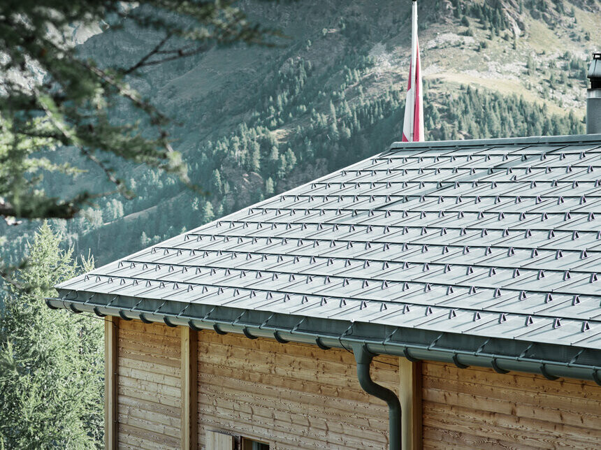 Sveitserhus tekket med PREFA takplate og med PREFA takrenne som er sikret med tverrstang.