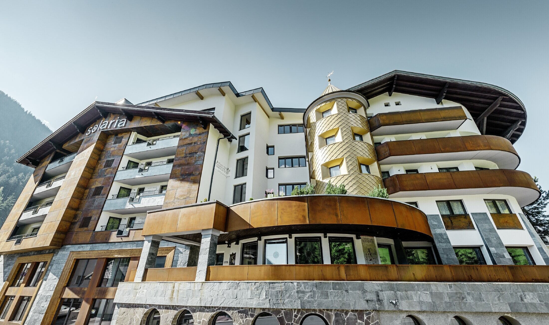 traditionelles Hotel in Ischgl mit Holzbalkonen und Holzfassade und einem Turm mit goldenen Alu-Rauten von PREFA