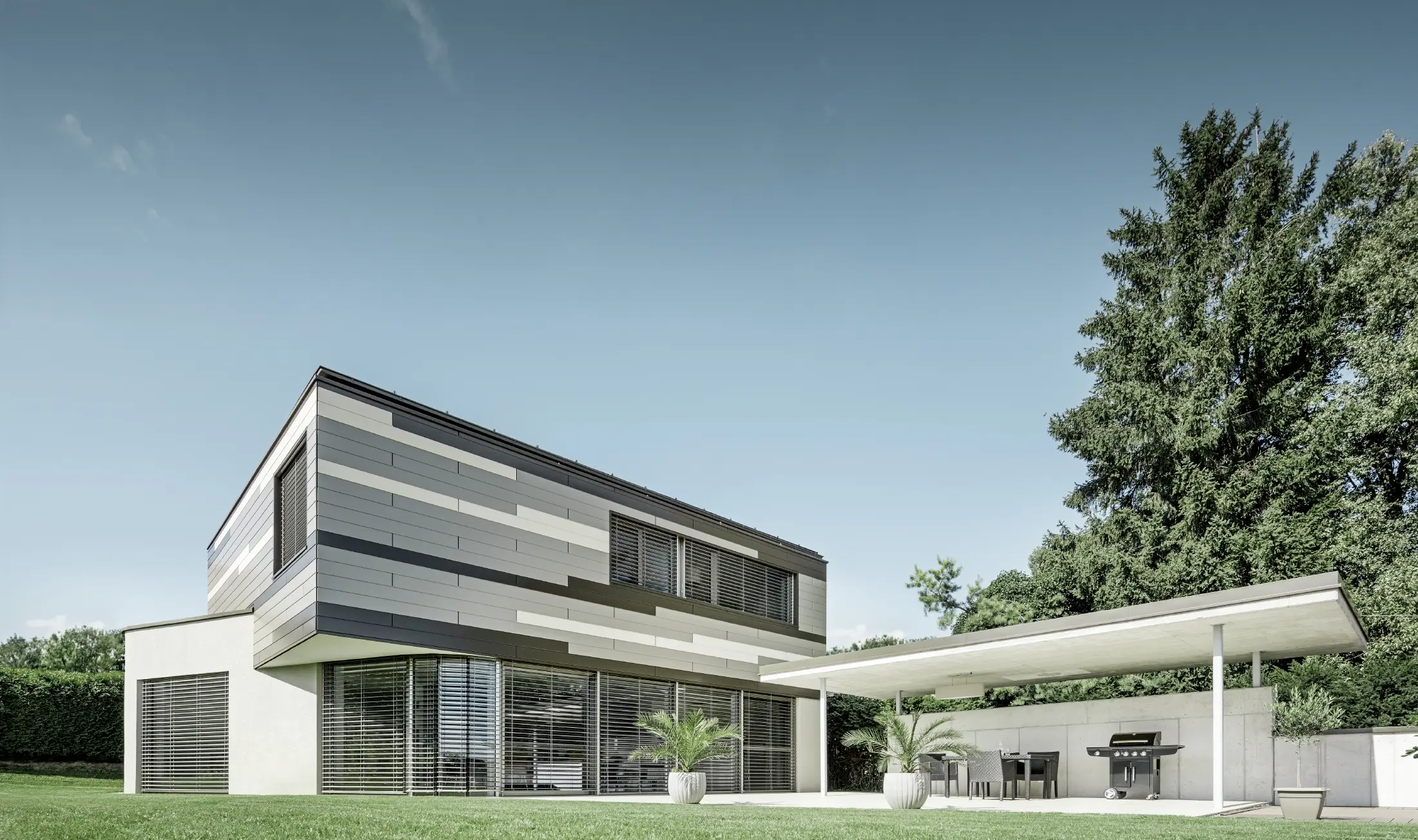 Modernes Einfamilienhaus mit Flachdach und überdachter Terrasse mit einer individuell gestalteten Aluminiumfassade aus Sidings in braun, bronze und elfenbein von PREFA