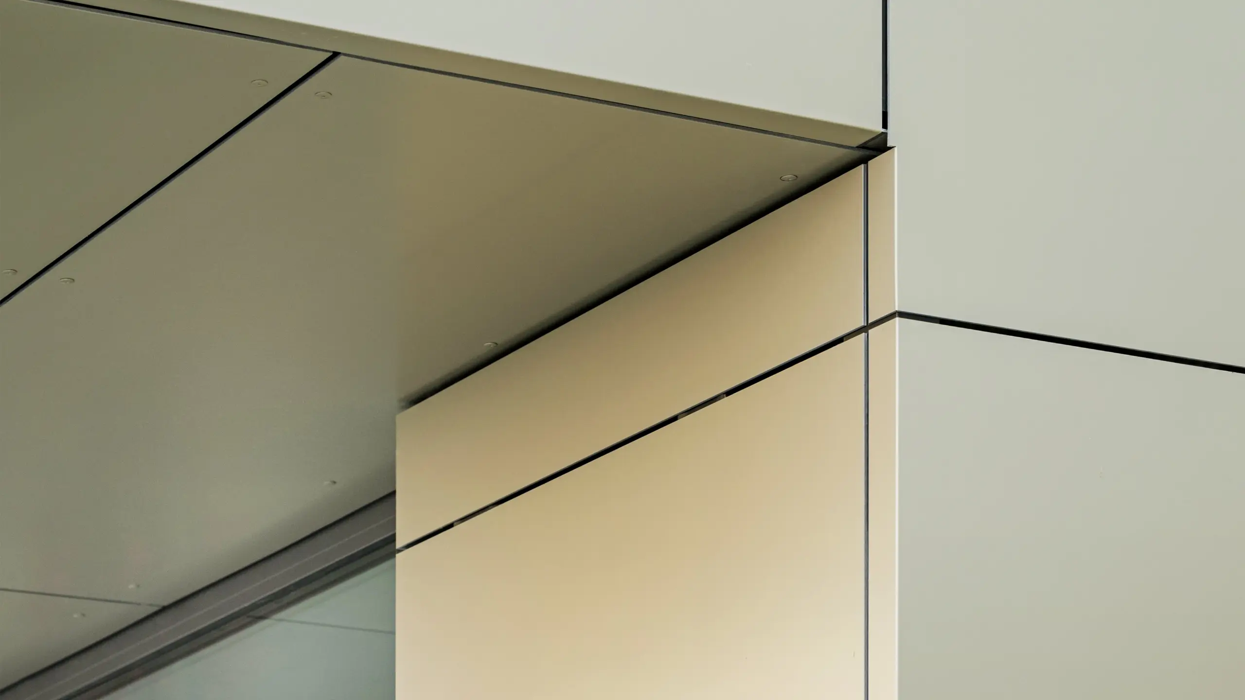 Eine Detailansicht der Fassade des Rathauses in Alzenau zeigt die präzisen Kanten und Übergänge der PREFA-Aluminiumverbundplatten in Bronze. Die Platten sind perfekt miteinander verbunden und erzeugen klare, moderne Linien. Der metallische Glanz der Platten wird durch feine Fugen und minimalistische architektonische Details betont und verleiht der Fassade ein elegantes und zeitgemäßes Erscheinungsbild.