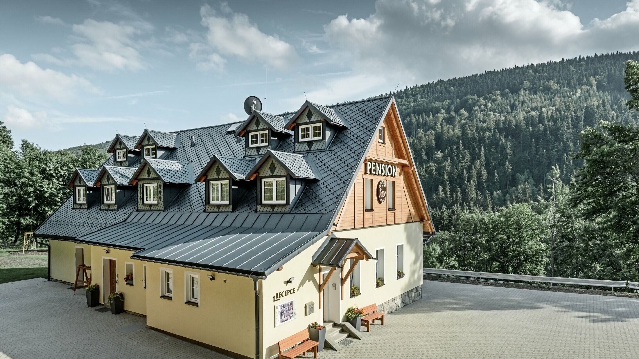 Vertshus i Tsjekkia med bratt tak og mange kobbhus dekket med aluminiumstak fra PREFA, skjellete rombetak med snøbeskyttelse