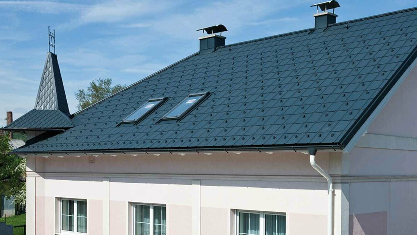 Hus etter renovering av taket med PREFA takplate i Østerrike – før Eternit-fibersement med tårn og rosa fasade