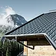 PREFA takpanel under alpine forhold - takpanel i antrasitt lagt på hytte i Lech am Arlberg med fjellene i bakgrunnen; PREFA takrenne i antrasitt; trefasade