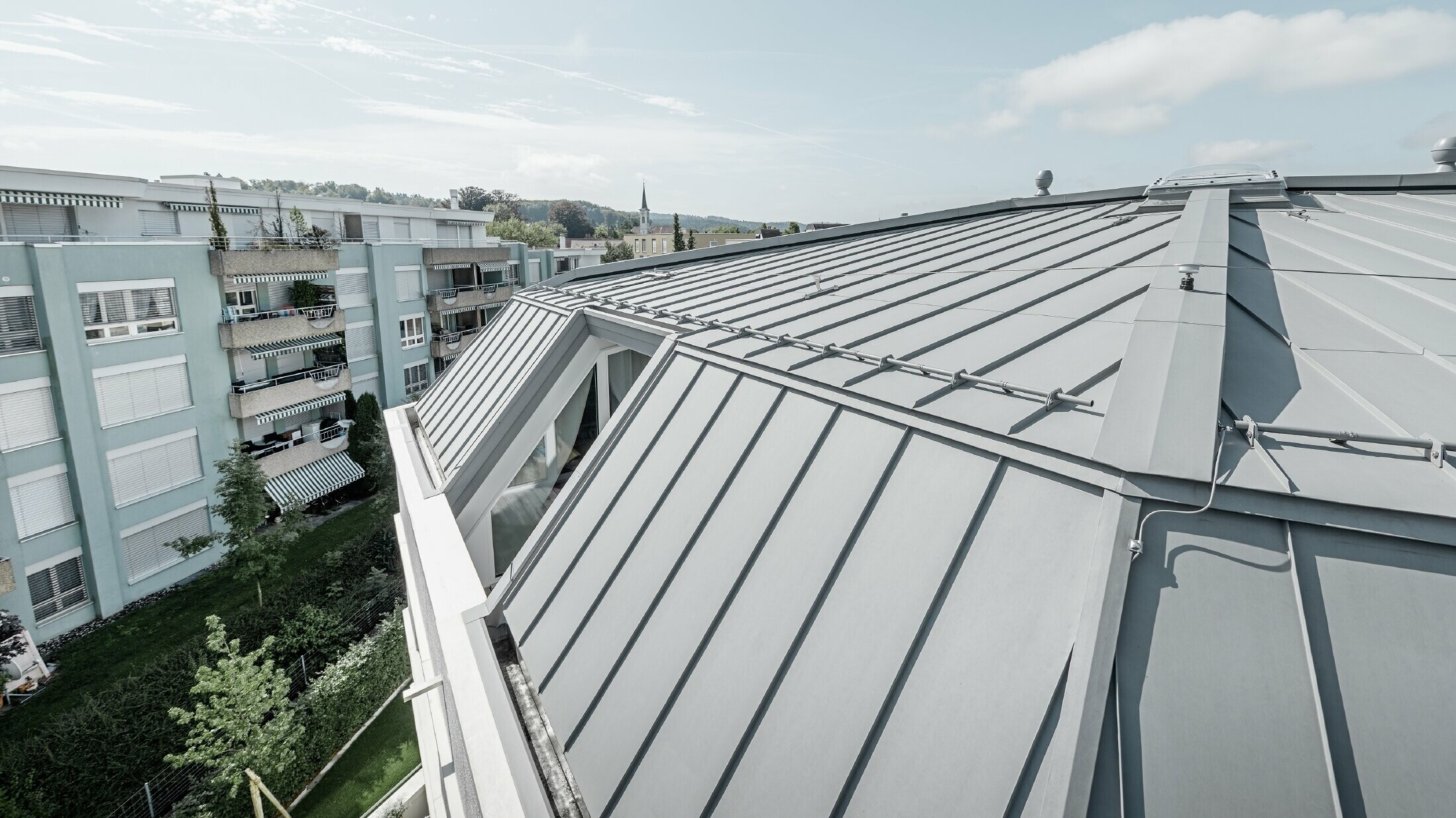 Detaljvisning av takflaten på et appartementshus. Ståfalstak utført med PREFA Prefalz i patinagrå.