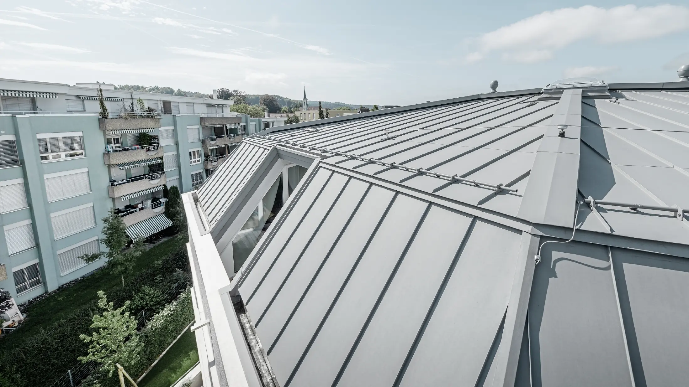 Detaljvisning av takflaten på et appartementshus. Ståfalstak utført med PREFA Prefalz i patinagrå.