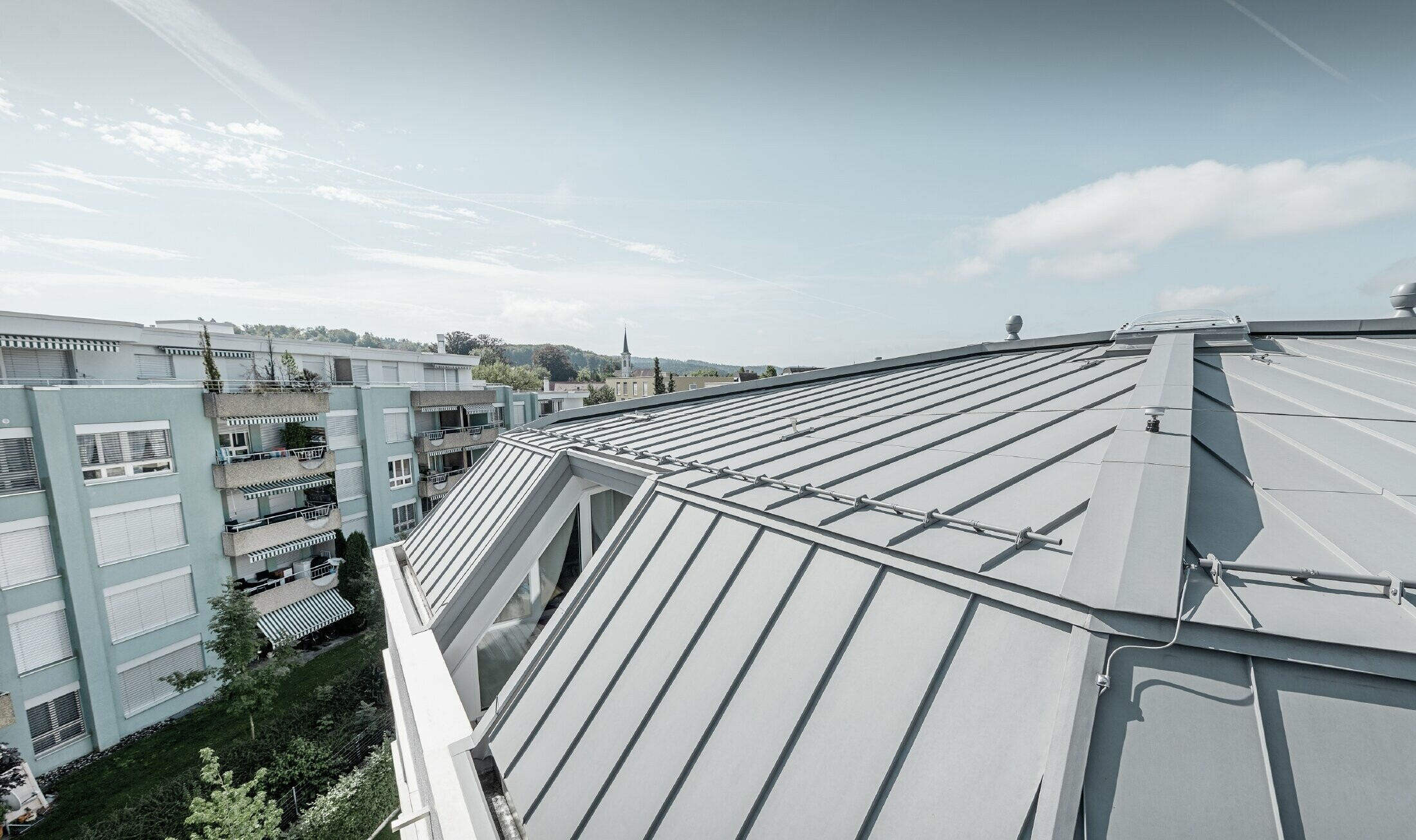 Detaljvisning av takflaten på et appartementshus. Ståfalstak utført med PREFA Prefalz i patinagrå.