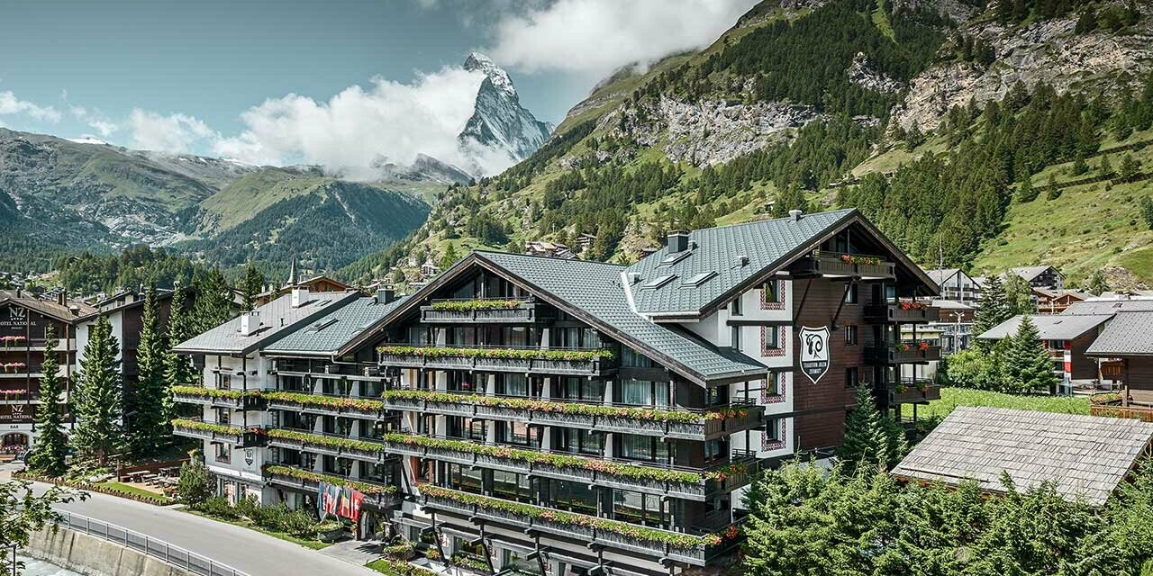 Hotelalpenhof in Zermatt mit dem Matterhorn im Hintergund, Balkonen, dunkler Holzfassade und einem PREFA Aluminiumdach in anthrazit