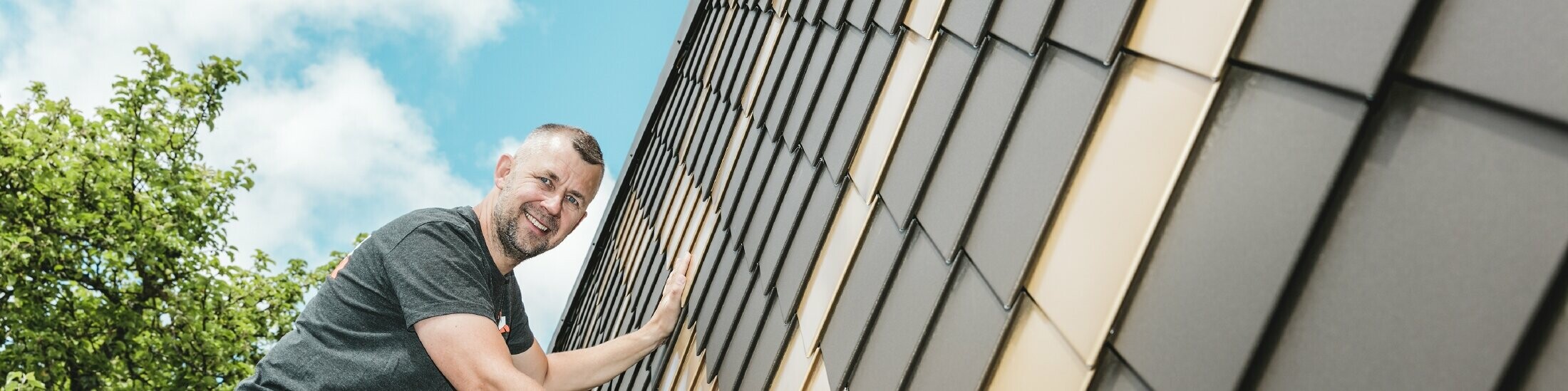 PREFA Handwerker in Ihrer Nähe an einer Fassade mit PREFA Wandrauten in Braun und Mayagold.