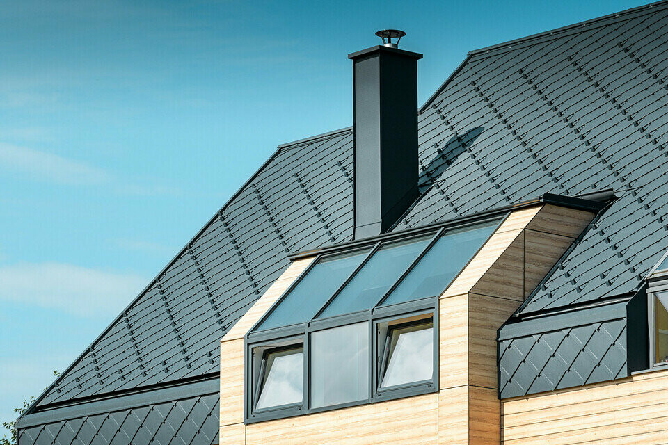 Einfamilienhaus mit Satteldach ohne Dachvorsprung mit einer Fassade in Holzoptik und einem Aluminiumdach in anthrazit