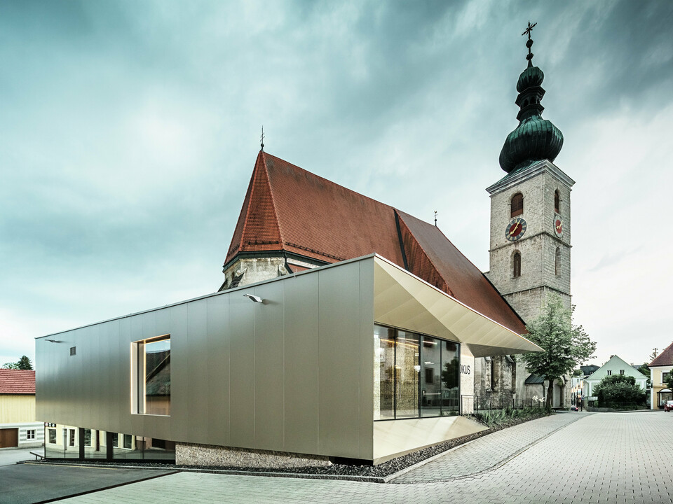Die seitliche Ansicht zeigt den filigranen Dachüberstand, realisiert mit hochwertigen PREFA Aluminium Verbundplatten. Die exakte Verarbeitung ermöglicht eine moderne Optik mit klaren Linien und unterstreicht die architektonische Verbindung zwischen Alt und Neu.