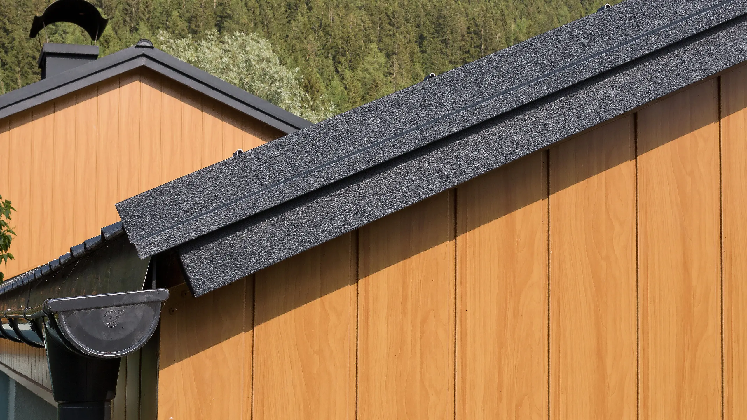 Gavlkledning med aluminium-sidings fra PREFA i natureik vertikalt montert med en PREFA-takrenne i antrasitt.
