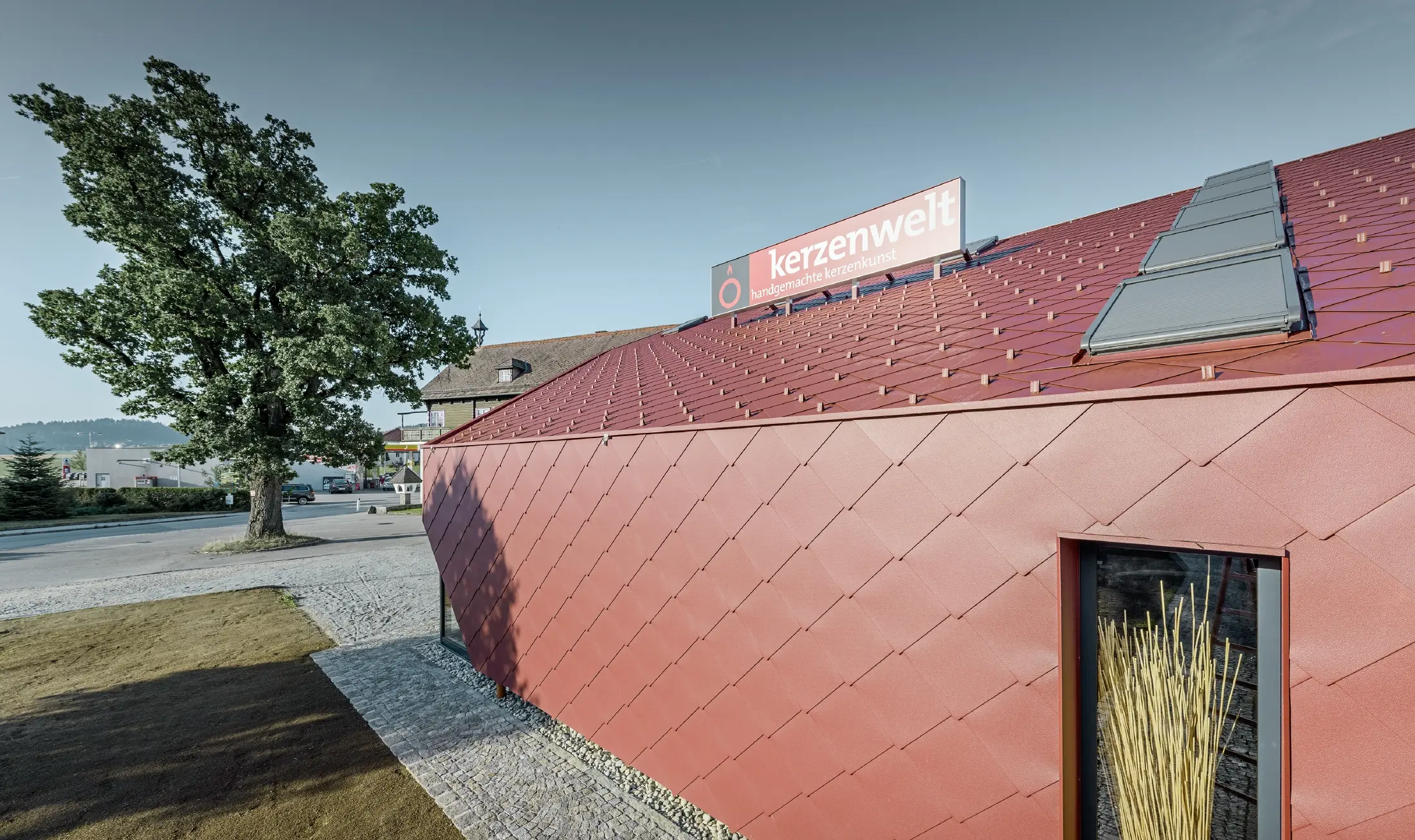 Kerzenwelt i Schlägl er kledd på nytt helt rundt med PREFA rombe. Takkledningen og fasadekledningen er utført med rombe 44 × 44 i oksydrød.