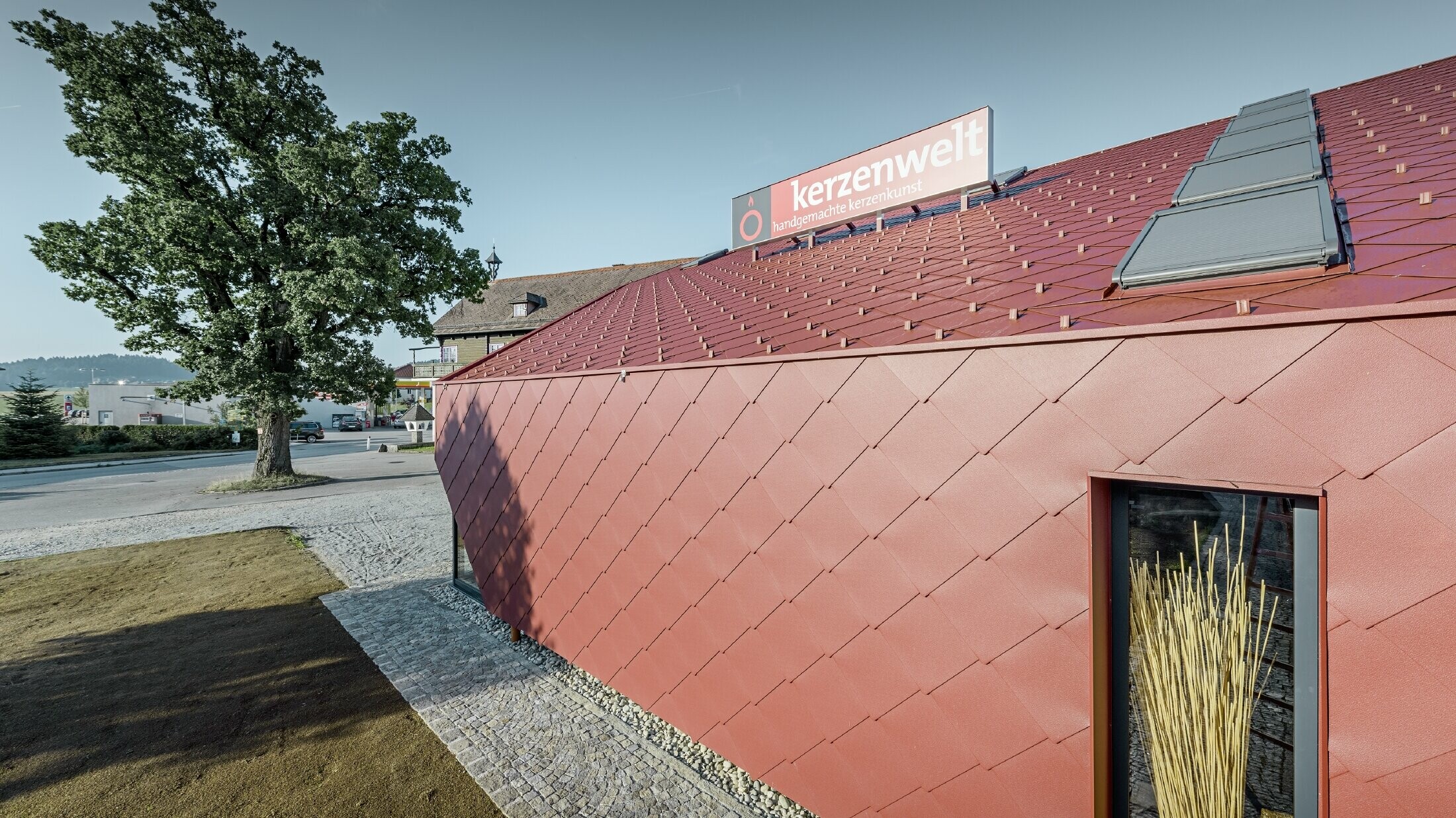Kerzenwelt i Schlägl er kledd på nytt helt rundt med PREFA rombe. Takkledningen og fasadekledningen er utført med rombe 44 × 44 i oksydrød.