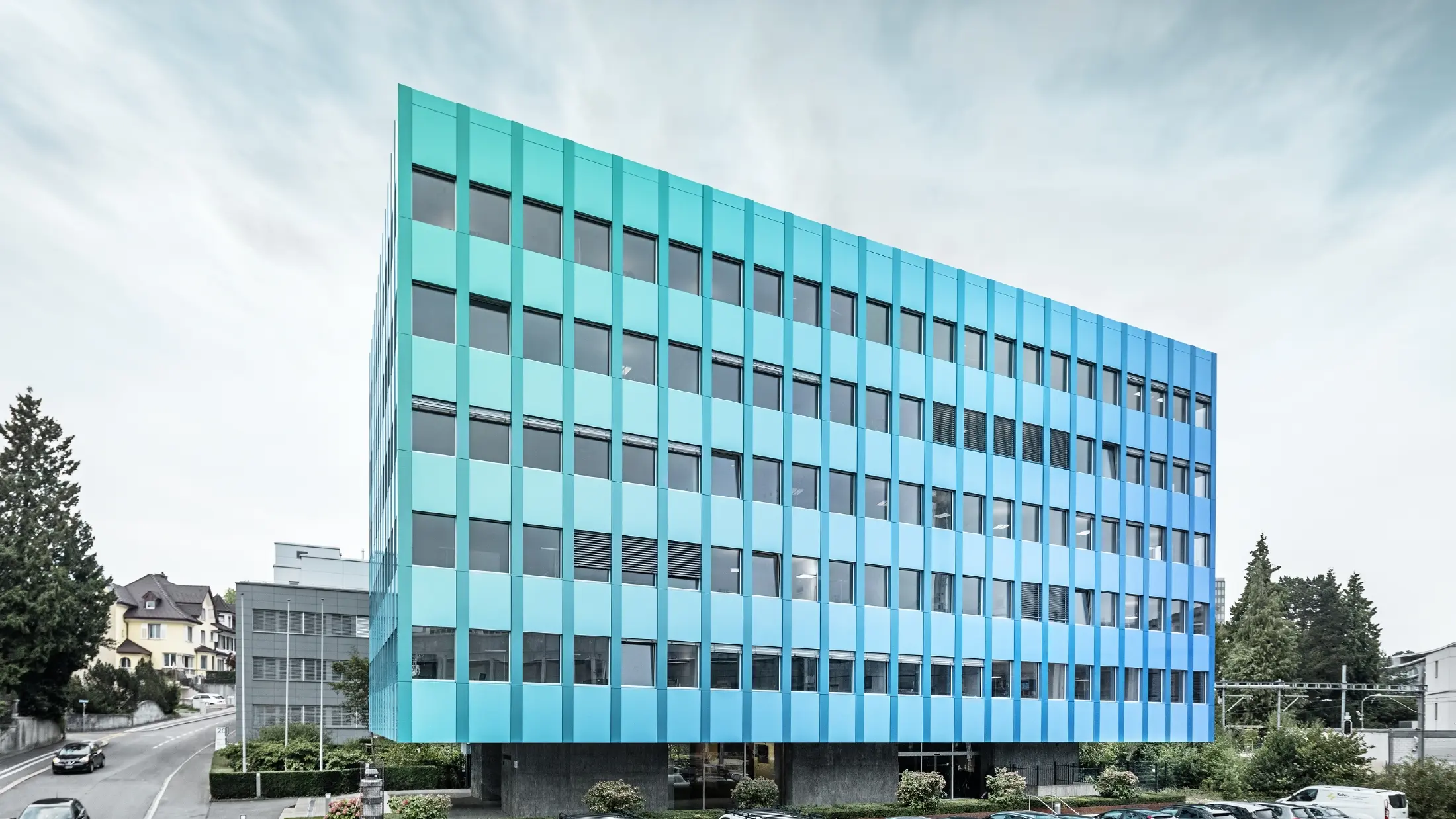 Sidevisning av Wielandhaus i Aarau. Fasaden er kledd med PREFABOND aluminiums-komposittplate fra PREFA, som får et blågrønt skimmer takket være en spesiell lakkeringsbehandling.