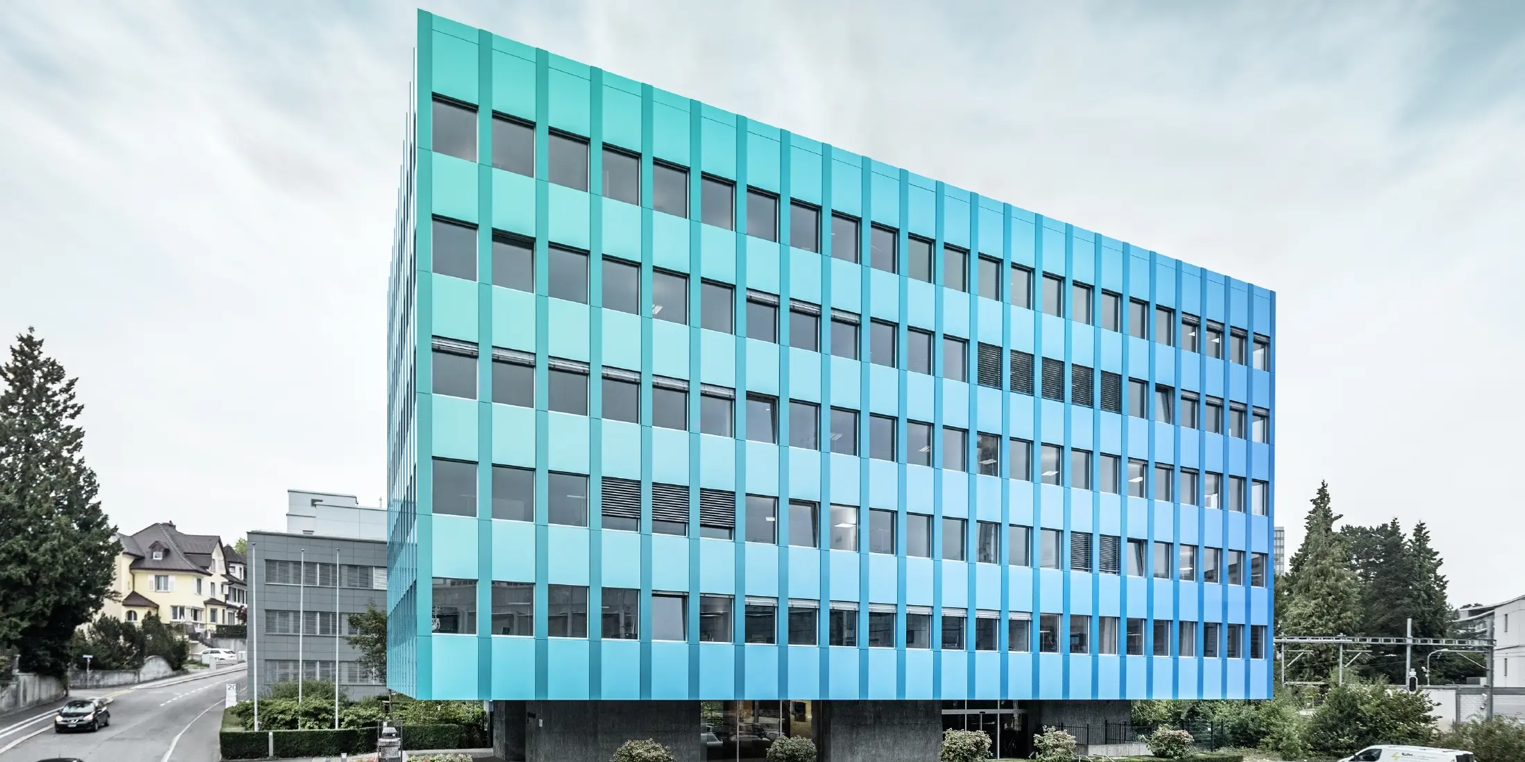 Sidevisning av Wielandhaus i Aarau. Fasaden er kledd med PREFABOND aluminiums-komposittplate fra PREFA, som får et blågrønt skimmer takket være en spesiell lakkeringsbehandling.