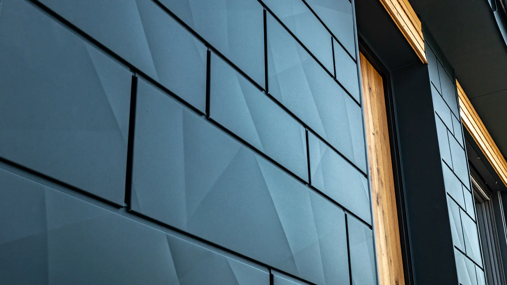 PREFA fasadepaneler med strukturert overflate; PREFA aluminium Siding.X i antrasitt kombinert med en trefasade.