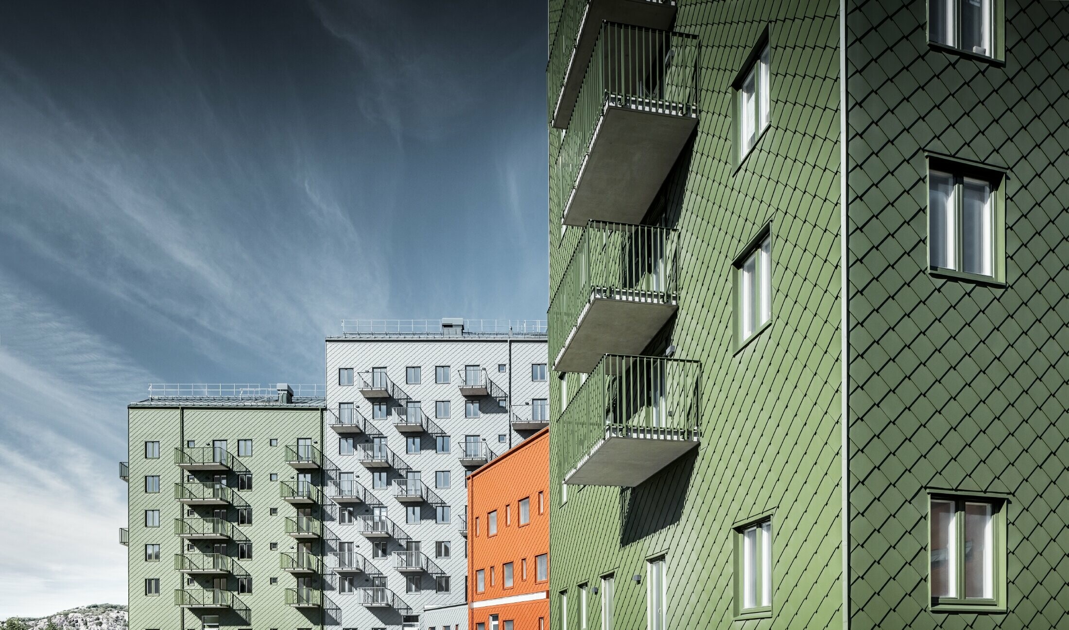 Flere bolighus ved siden av hverandre, kledd med PREFA veggrombe 29 × 29 i fargene teglsteinsrødt, olivengrønt, og lysegrått.