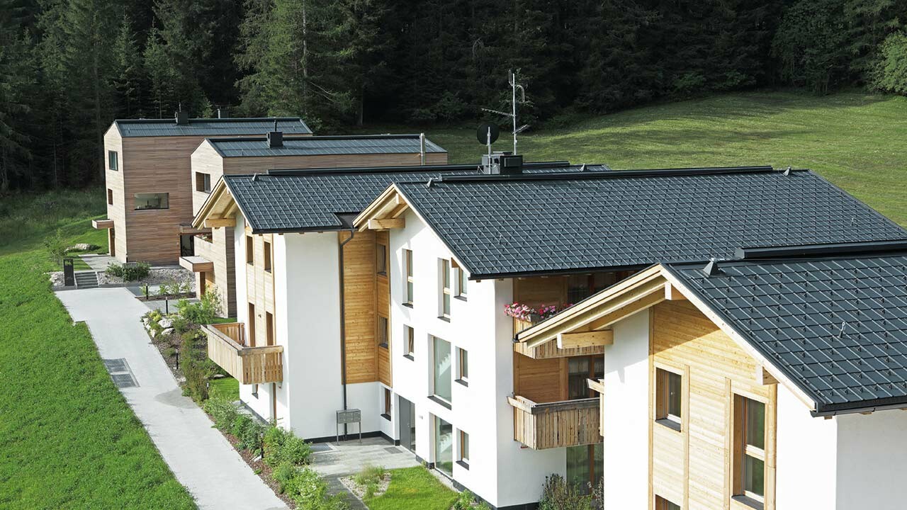 Foto av de fem bolighusene i Corvara, som er tekket med PREFA takpanel og stående fals i antracitt av stormsikkert aluminium.