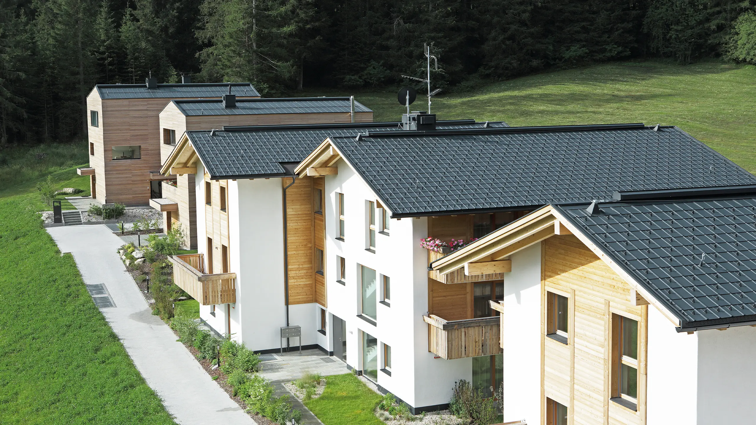 Foto av de fem bolighusene i Corvara, som er tekket med PREFA takpanel og stående fals i antracitt av stormsikkert aluminium.