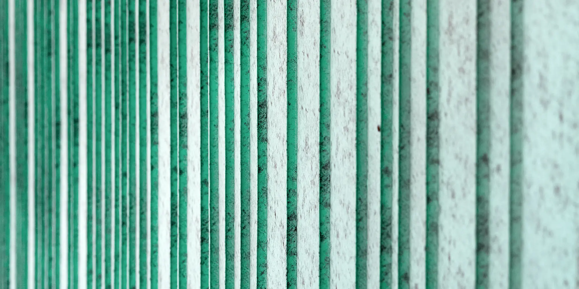 Detailansicht der patinagrünen Aluminium Fassade, rhythmisiert mit unterschiedlich breiten Scharen. Die Farbe erzeugt eine gesprenkelte Optik.