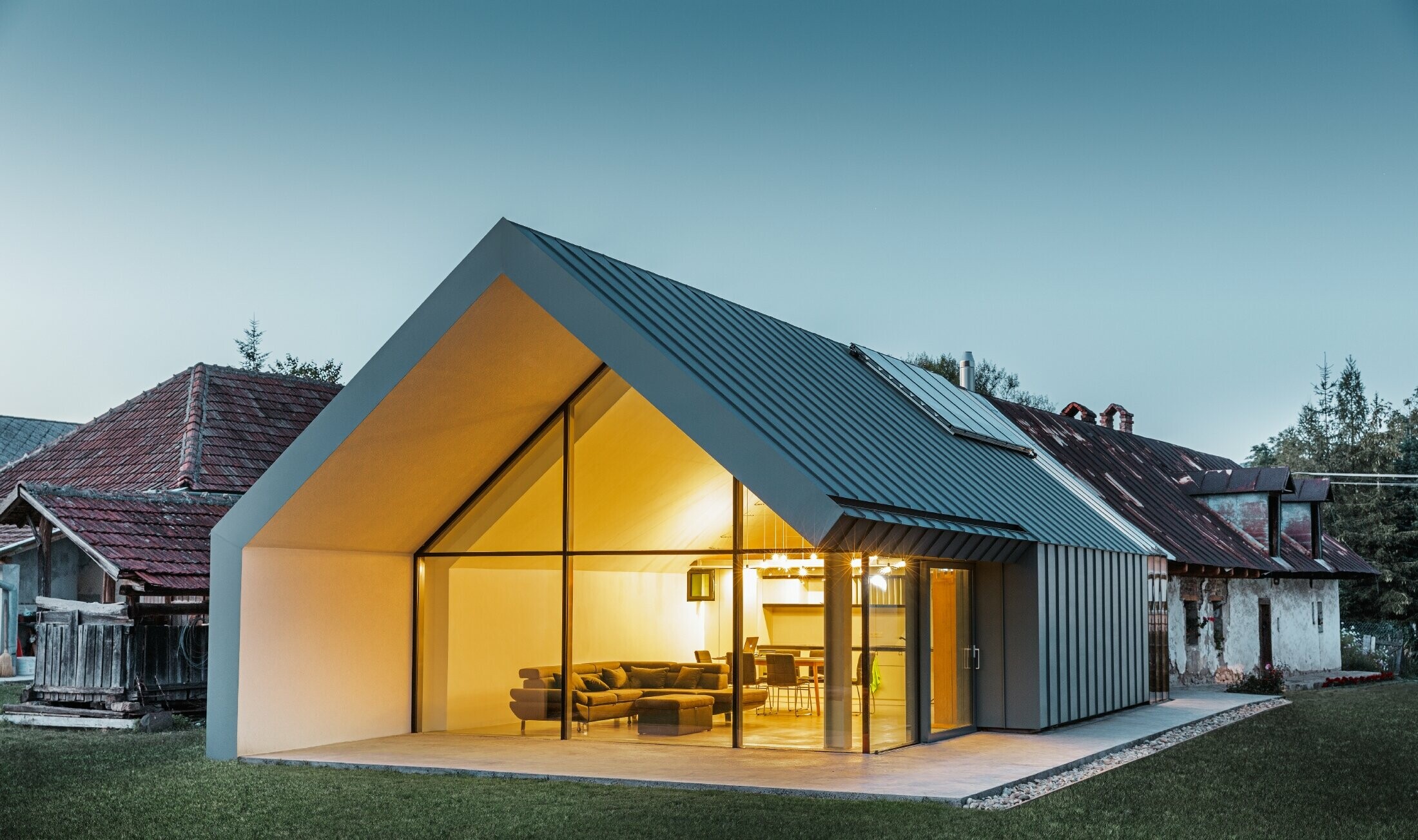 modernes neues Architektenbüro und Einfamilienhaus im Anschluss an ein altes Bauernhaus mit Steinfassade, verkleidet mit Stehfalz und Winkelstehfalz von PREFA in hellgrau