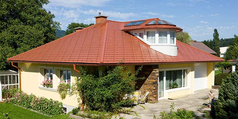 Enebolig med valmet tak og kvistvindu dekket med PREFA aluminiumstakshingel i teglsteinsoptikk, mursteinsrød.